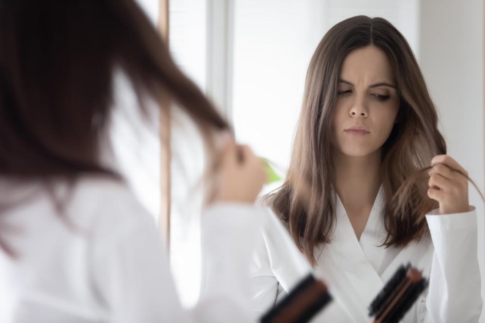 Girl worried about hair loss in front of a mirror