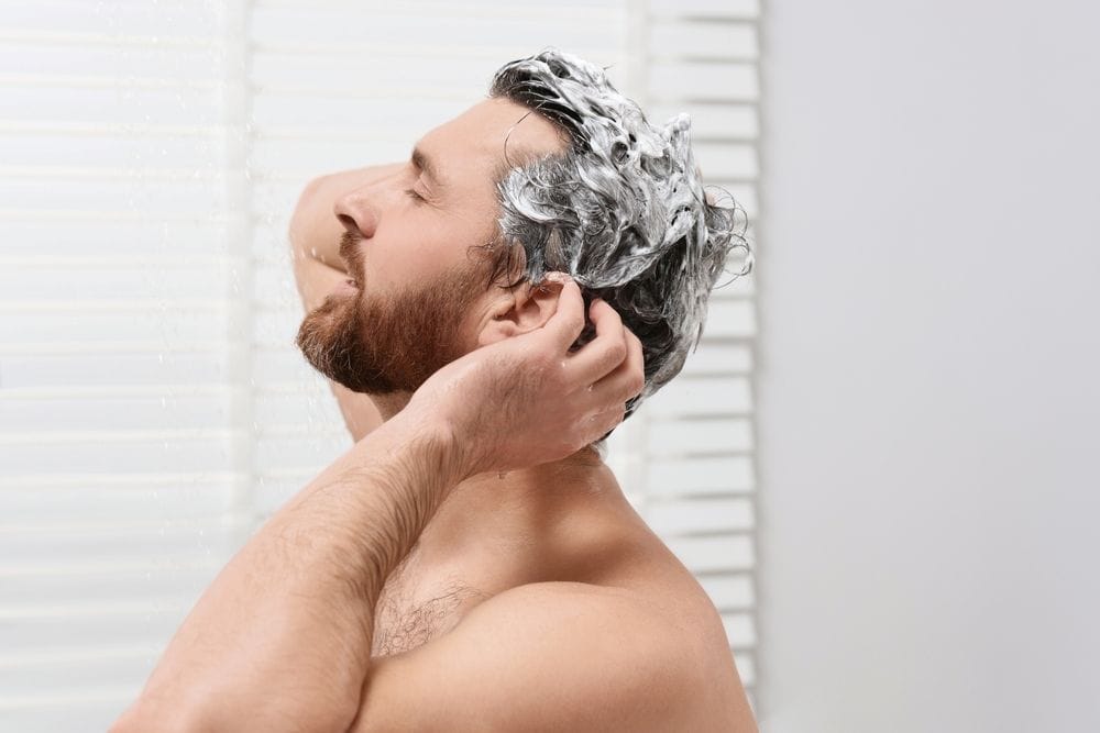 Man washing hair to prevent pimples on scalp and maintain scalp hygiene