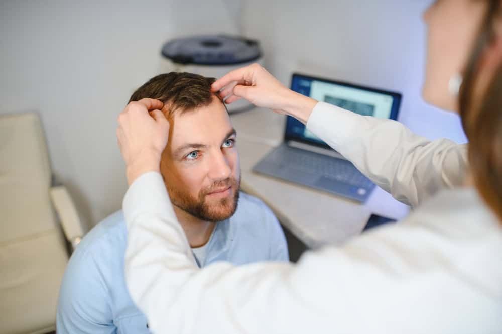 Caucasian man receiving a scalp assessment before a hair transplant consultation